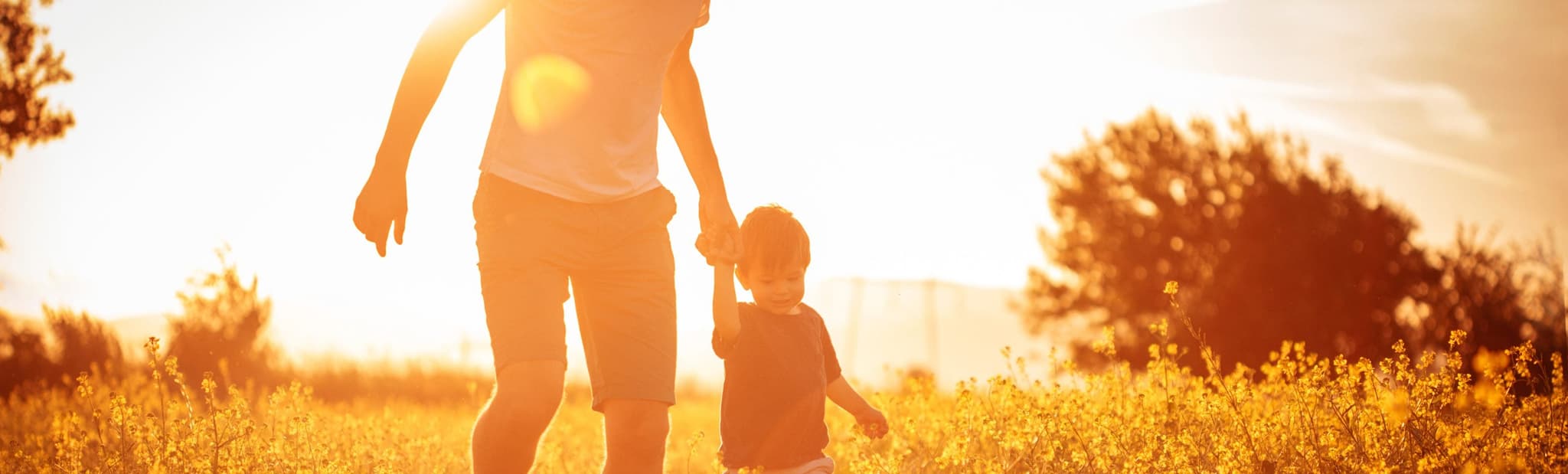 father and child walking through field