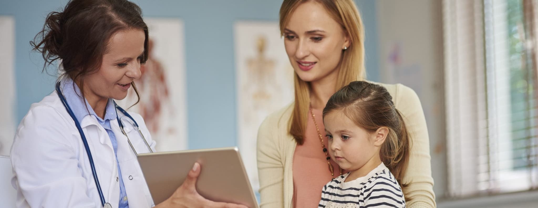 Picture of doctor showing ipad results to mother and child